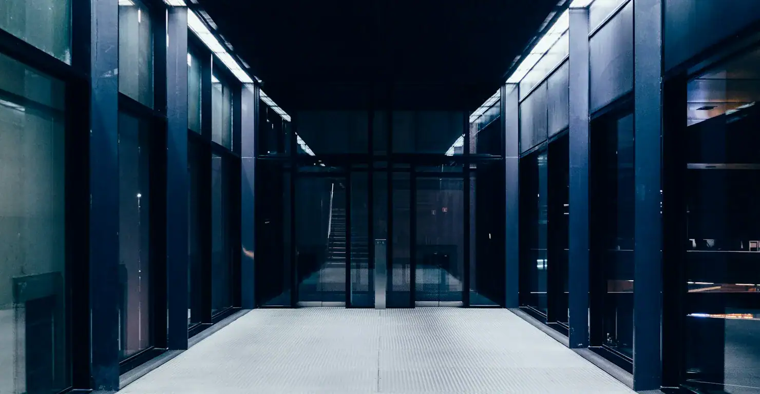 Couloir sombre aux parois vitrées éclairé par des néons, illustration du comparatif AWS vs Azure vs Google Cloud