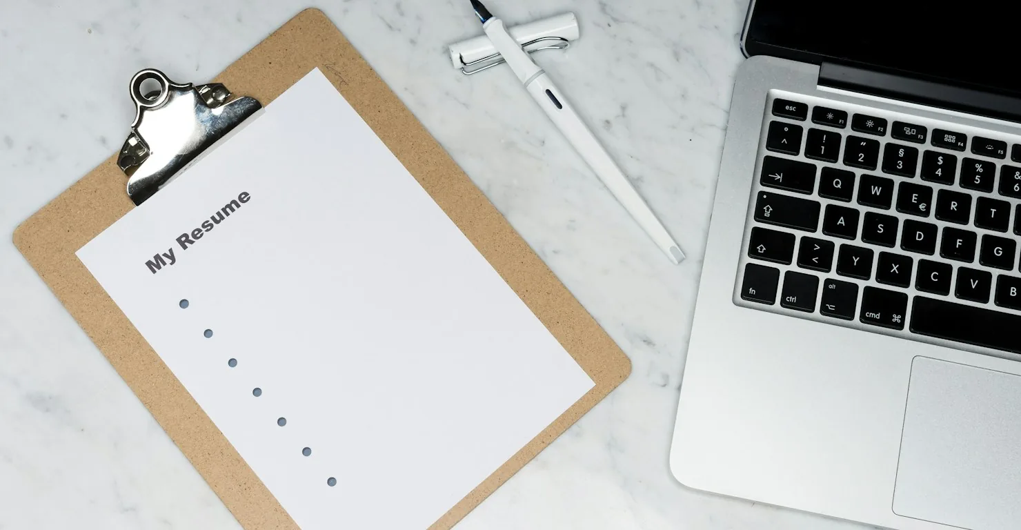 Feuille intitulée My Resume sur un porte-bloc à côté d'un ordinateur portable, pour rédiger un CV de développeur