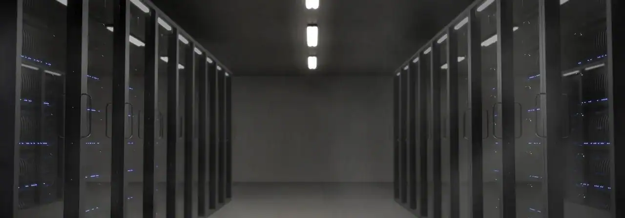 Allée d'une salle de serveurs sombre, bordée de baies aux voyants bleus