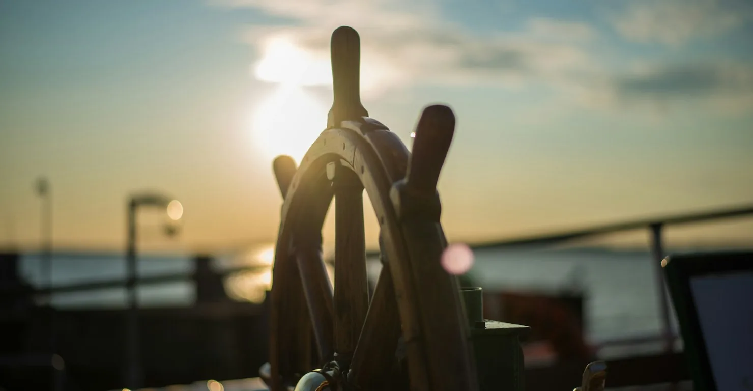 Barre à roue en bois d'un navire au coucher du soleil, image du timonier dont Kubernetes tire son nom